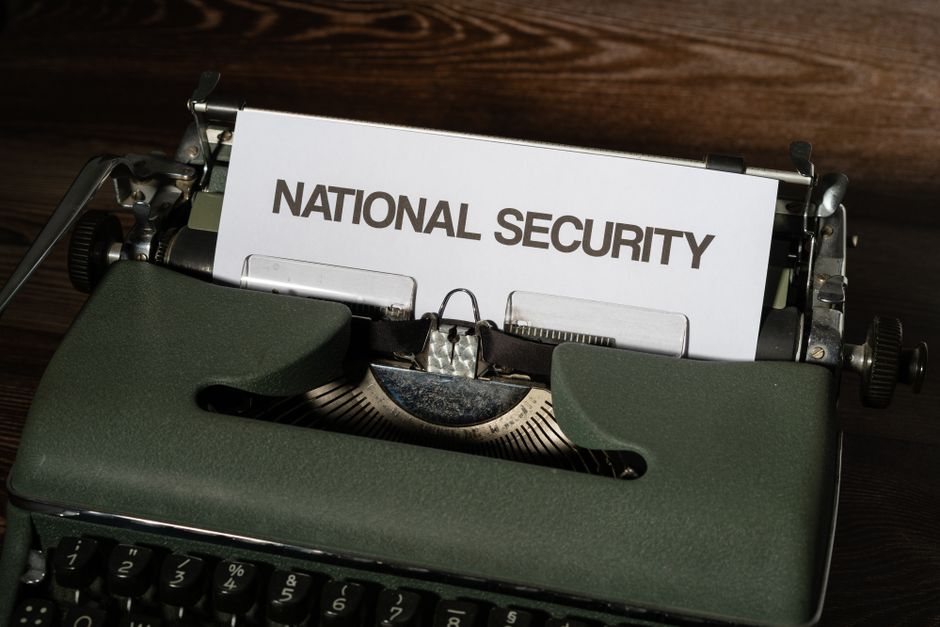 Máquina de escrever antiga com uma folha de papel contendo o texto 'National Security', simbolizando temas de segurança nacional e confidencialidade.