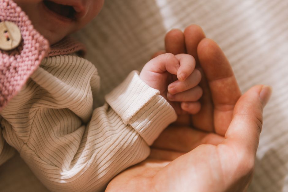 Imagem de uma criança segurando a mão de um adulto, simbolizando vínculo e cuidado parental.