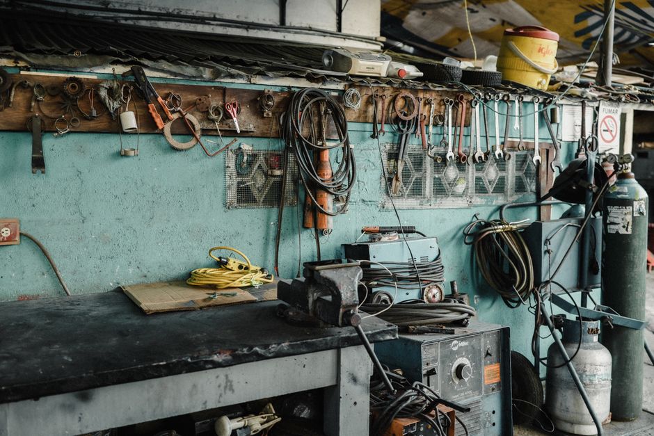 Imagem de um espaço de oficina com ferramentas e equipamentos industriais, representando manutenção e reparo técnico.