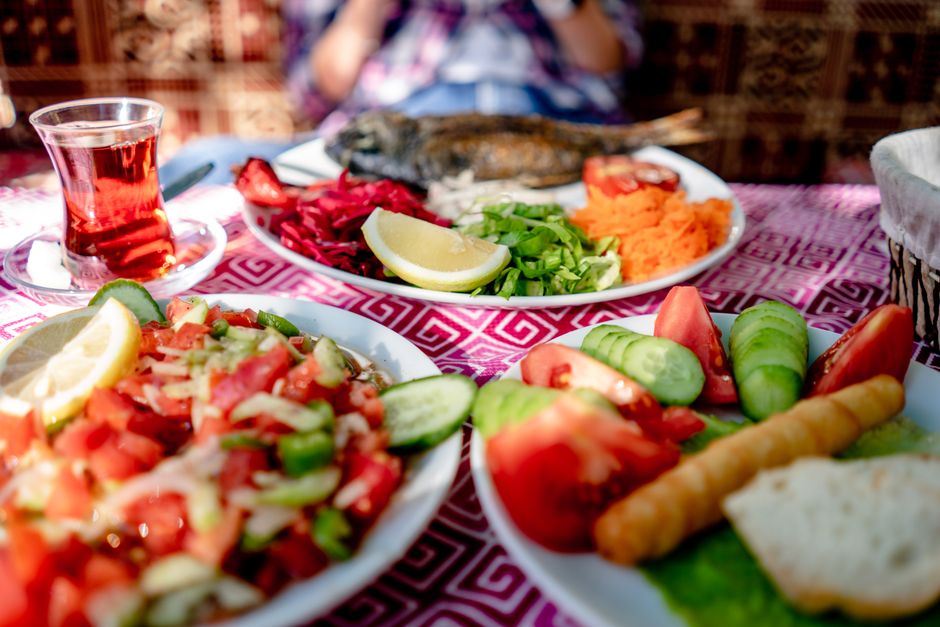 Mesa com pratos tradicionais de comida árabe, incluindo saladas, peixes e acompanhamentos, em ambiente festivo.