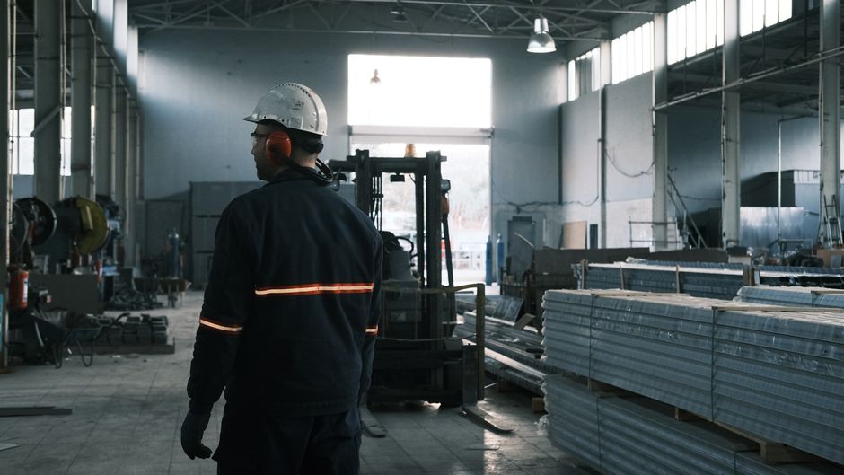 Profissional de segurança em uma fábrica industrial, com foco na vigilância e controle do ambiente de trabalho.