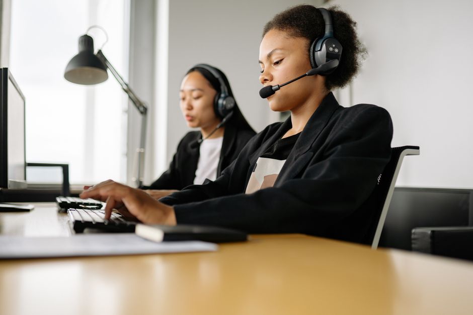 Duas atendentes em um call center utilizando headsets, transmitindo profissionalismo e atendimento ao cliente.