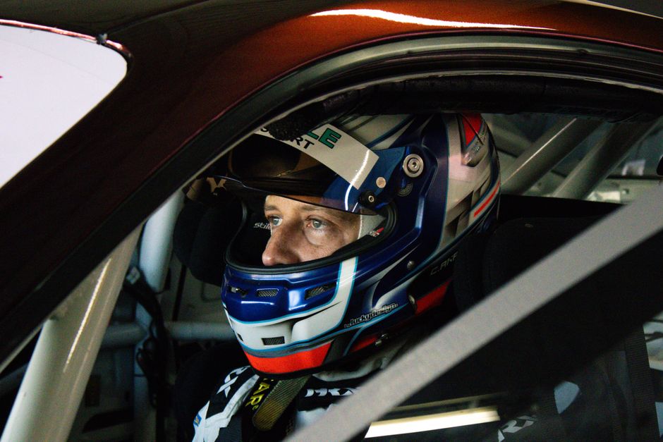 Piloto de corrida dentro do carro, preparado para uma competição automobilística, focado e concentrado.