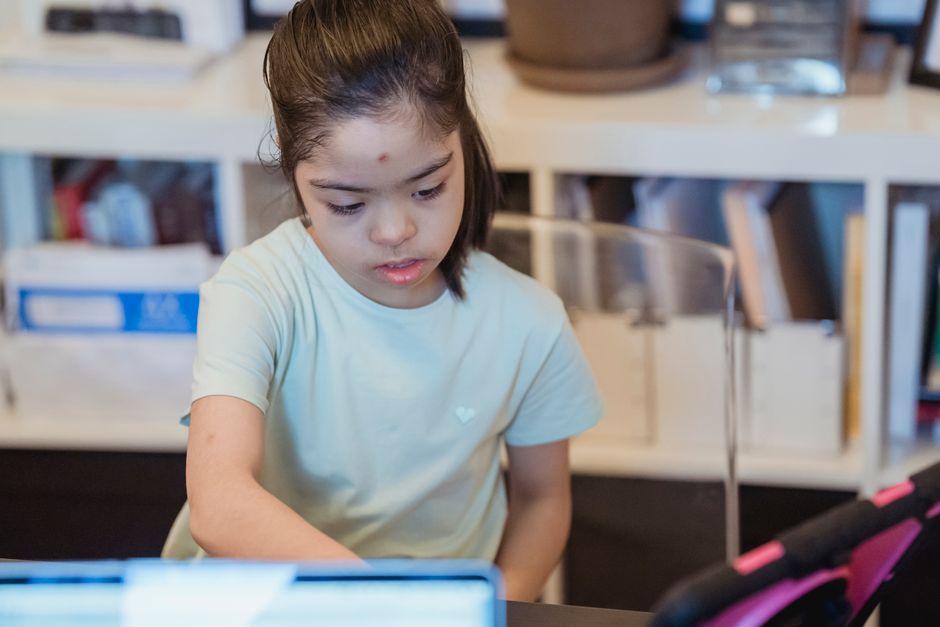 Menina concentrada estudando ou fazendo lição de casa em ambiente de sala de aula ou escritório doméstico.