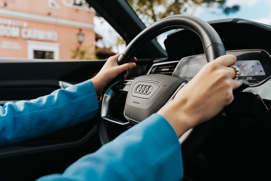 Pessoa dirigindo um carro da marca Audi, enfatizando a tecnologia e o conforto na condução.