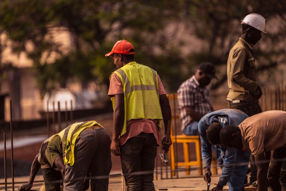 Imagem de trabalhadores na construção civil durante o pôr do sol, mostrando o esforço e a colaboração no setor de construção.
