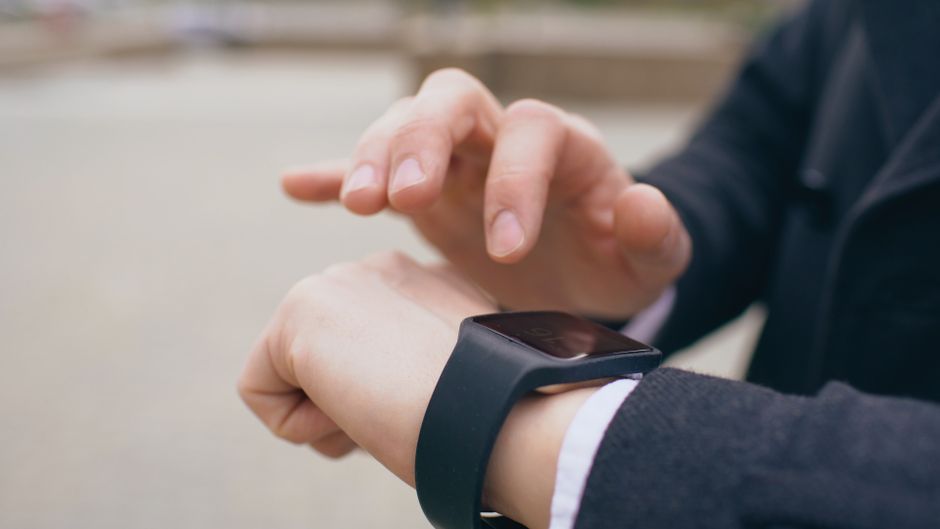 Imagem de uma pessoa verificando informações em um smartwatch, indicando o uso de tecnologia para monitoramento e gestão de atividades.