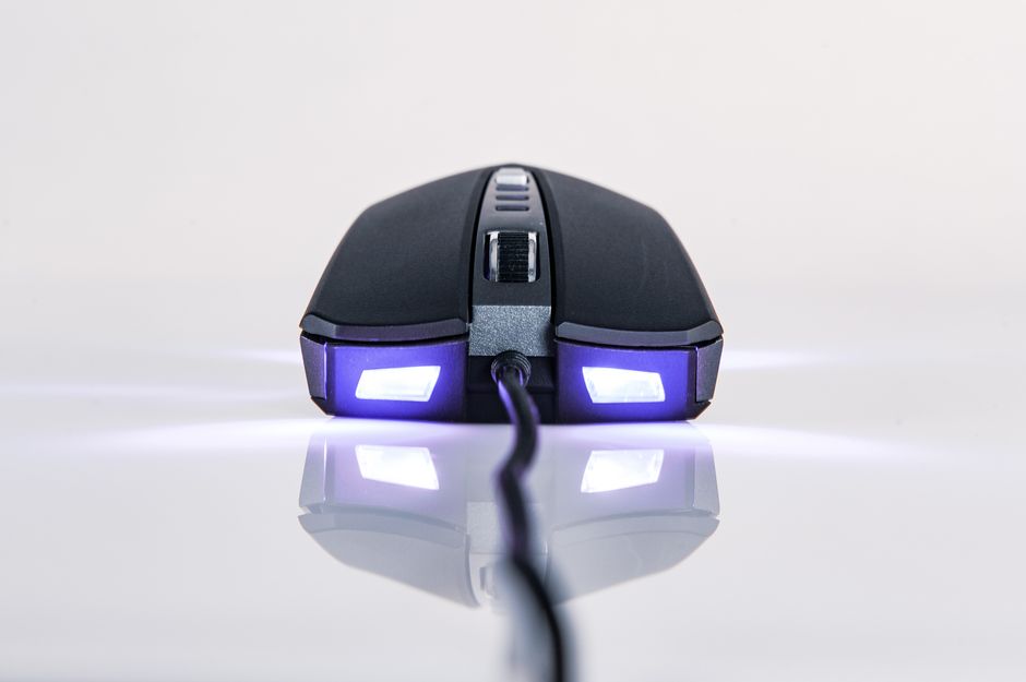 Imagem de um mouse de computador visto de trás, sobre uma superfície reflexiva, simbolizando tecnologia e trabalho digital.