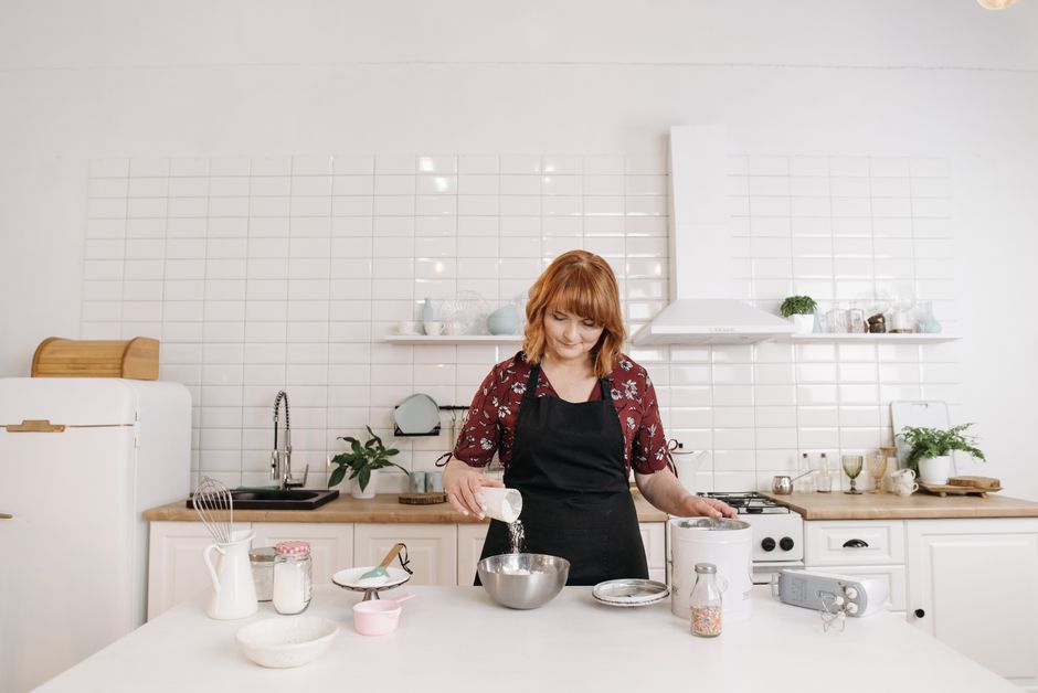 Mulher preparando receita na cozinha moderna, destacando o ato de cozinhar e organização do espaço culinário.
