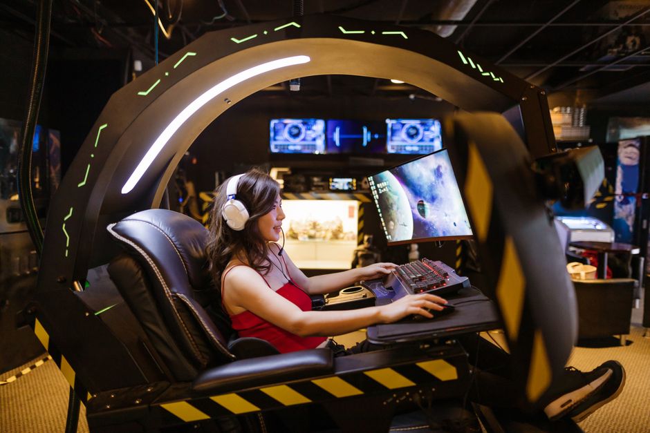 Pessoa jogando videogame em uma cabine de realidade virtual, destacando tecnologia e entretenimento digital.