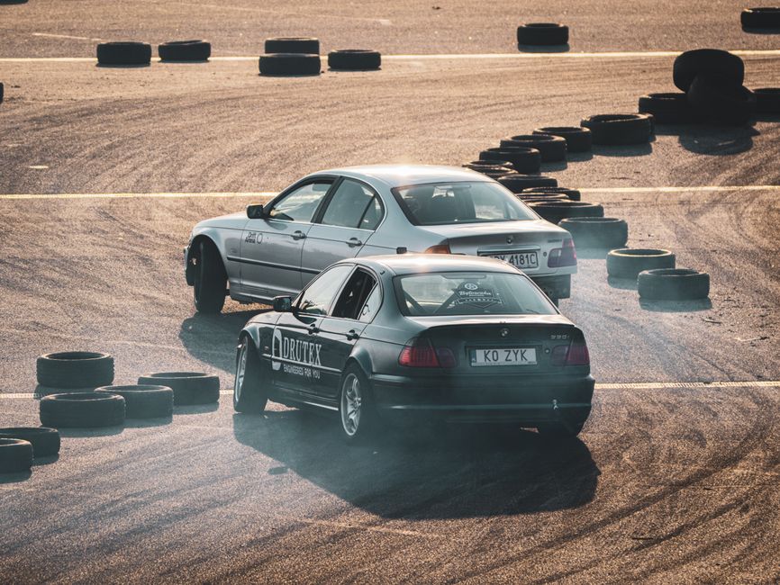Duas carros em uma pista de corrida com pneus espalhados, simbolizando um evento automotivo ou treinamento de pilotagem.