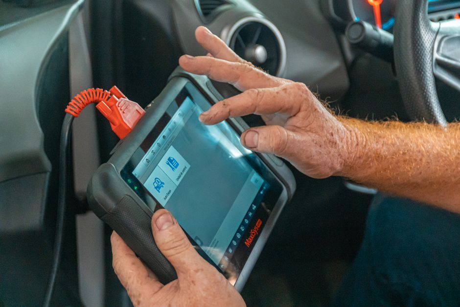 Pessoa utilizando um scanner automotivo para diagnóstico de veículo no interior de um carro