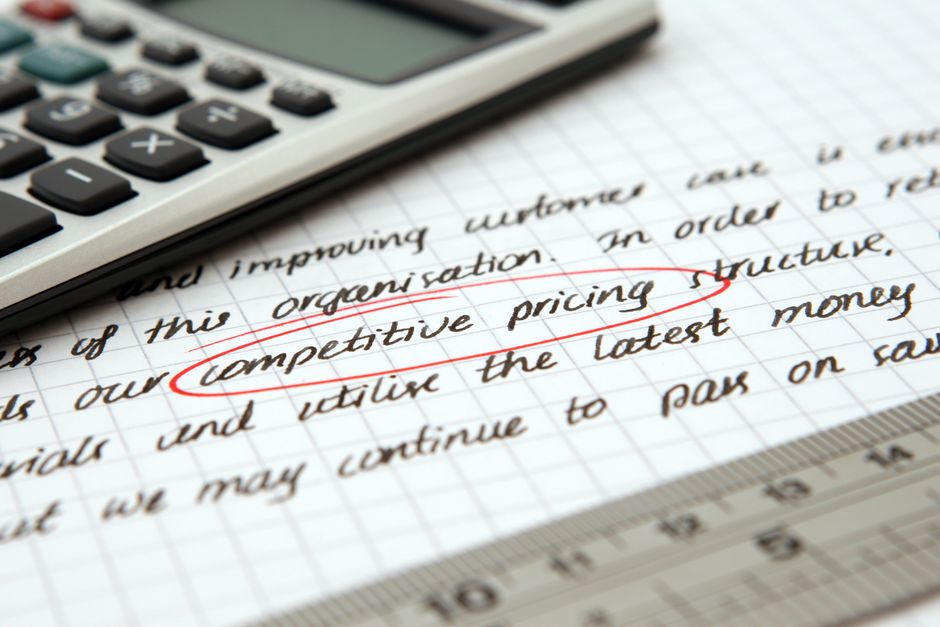 Foto de uma calculadora ao lado de uma página de anotações manuscritas, destacando a importância de precificação competitiva em estratégias de negócios.