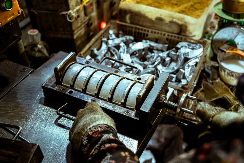 Imagem de uma máquina de processamento de alimentos em uma cozinha artesanal, com uma pessoa manipulando o equipamento, sugerindo produção manual e artesanal.