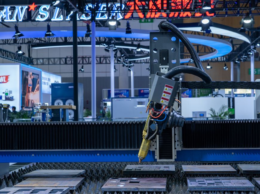 Imagem de uma máquina de corte de chapas metálicas em uma feira de tecnologia industrial, destacando avanços em automação e manufatura.