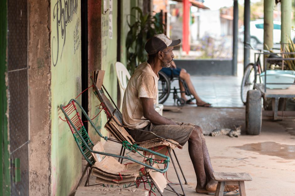 Homem sentado na rua, representando a rotina urbana e as condições sociais.
