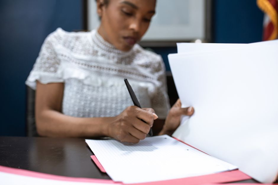 Mulher analisando e organizada documentos para planejamento ou gerenciamento de projetos.