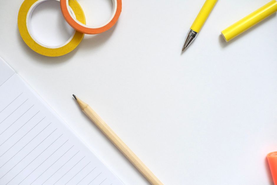 Imagem de materiais de escritório coloridos e canetas sobre uma superfície branca, ideal para artigos sobre organização e planejamento de trabalho.