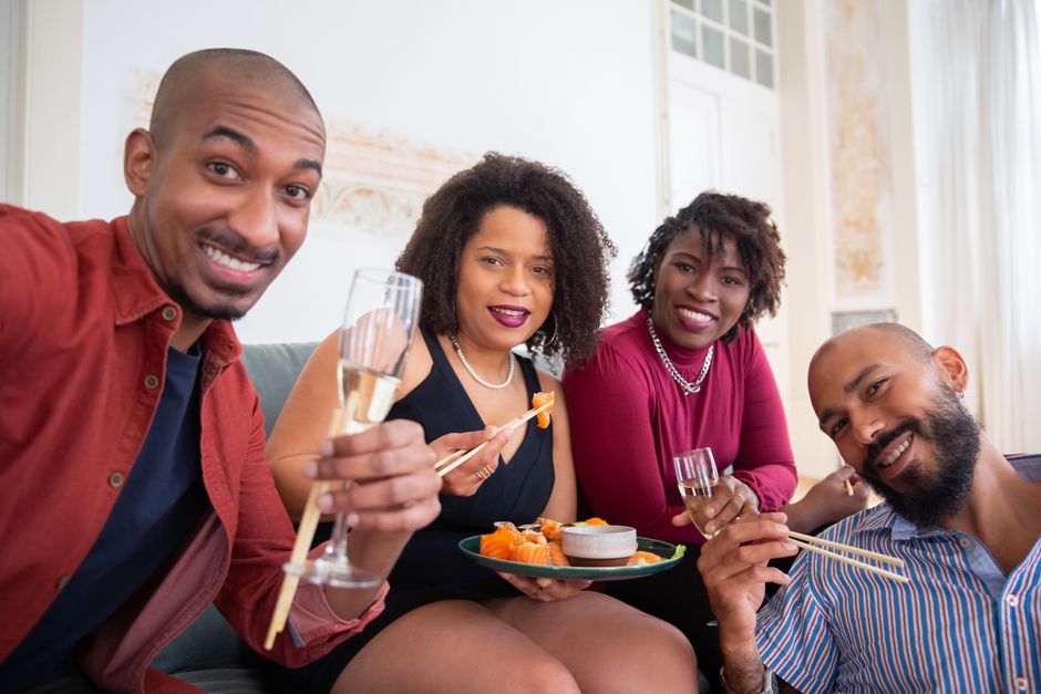 Grupo de amigos celebrando com sushi e vinho em um ambiente acolhedor, criando memórias e momentos de descontração.