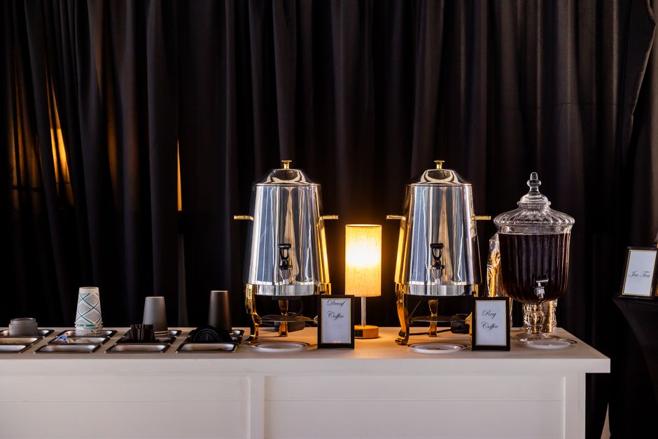 Estação de café elegante e bem organizada em um evento, destacando a preparação de bebidas quentes para os convidados.
