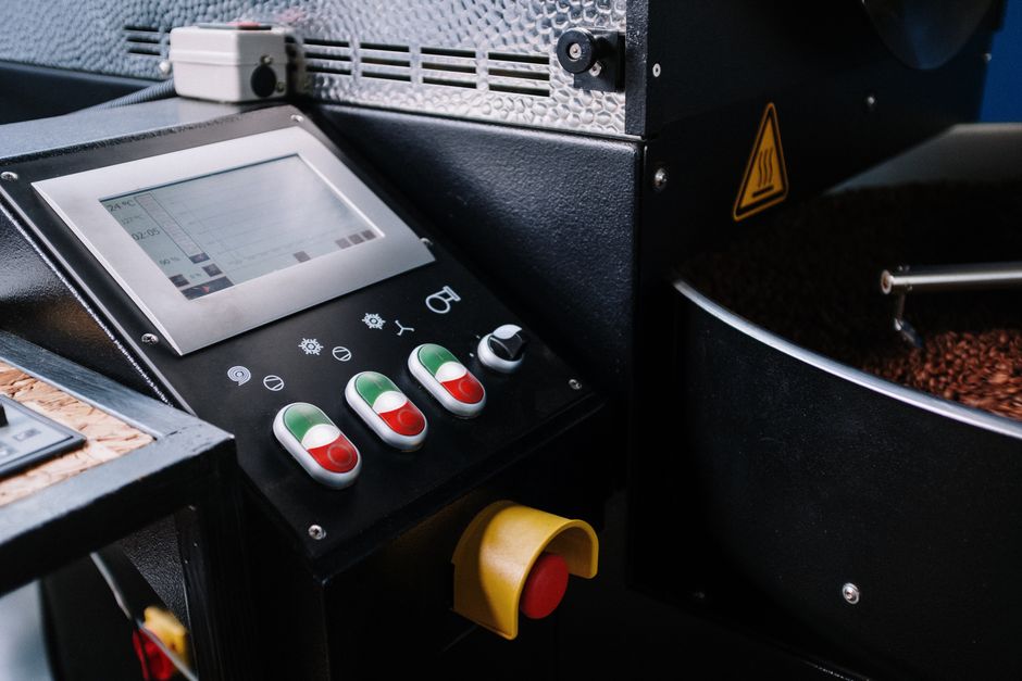 Máquina de torrefação de café industrial em operação, destacando o processo de preparo do café.