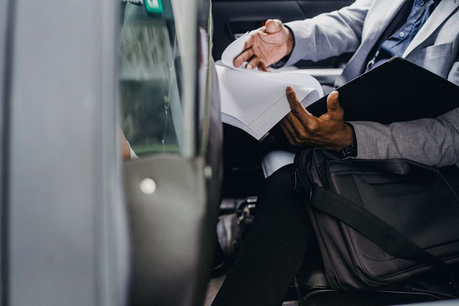 Homem de negócios revisando documentos importantes durante uma viagem de carro, simbolizando planejamento e estratégias empresariais em movimento.