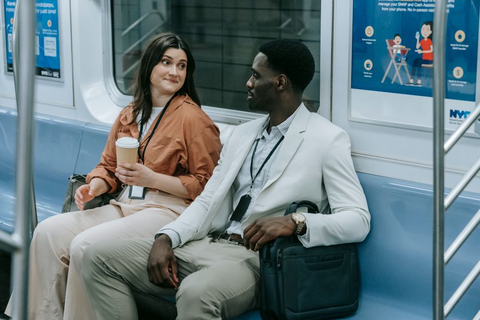 Duas pessoas em uma discussão amigável sentadas em um vagão de metrô, demonstrando uma interação social em transporte público.