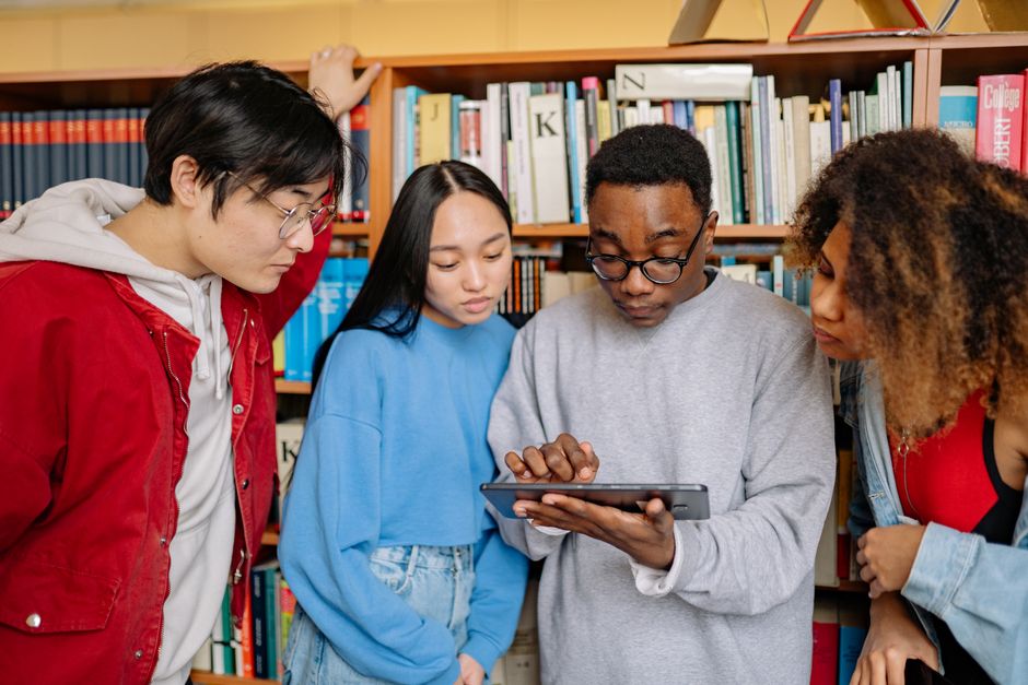 Grupo de jovens estudando e discutindo informações em uma biblioteca, explorando temas educacionais e de aprendizado coletivo.