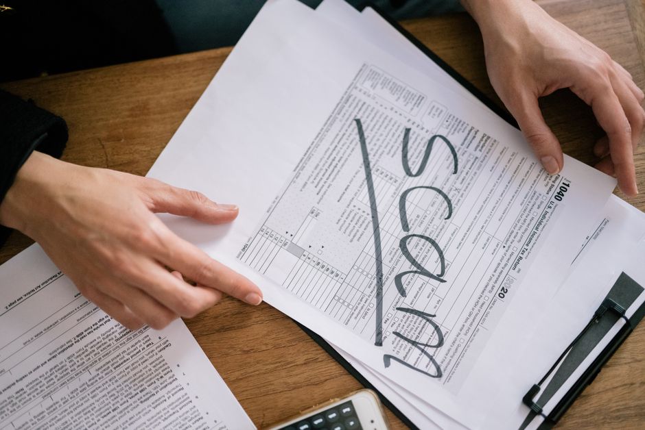Pessoa revisando documentos fiscais na mesa, simbolizando organização financeira e análises de impostos.