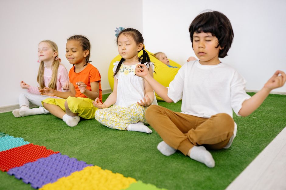 Crianças meditando em um ambiente interno, promovendo equilíbrio e bem-estar na infância.
