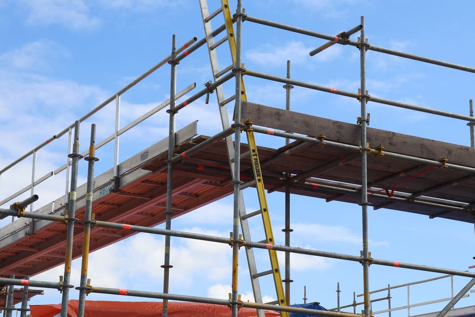 Estrutura de andaimes de construção civil contra um céu azul, simbolizando obras e infraestrutura em andamento.