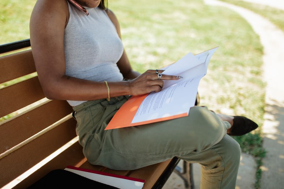 Mulher lendo documentos ao ar livre, simbolizando análise e tomada de decisão em ambiente externo.