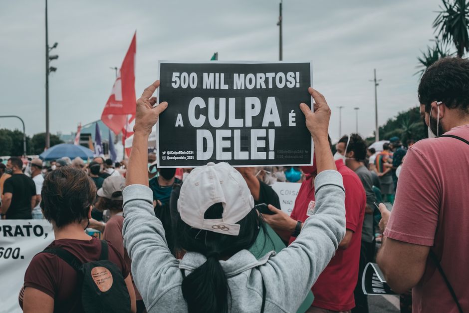 Mulher segurando cartaz em manifestação contra desigualdade e violência, evidenciando mobilização social e protesto político.