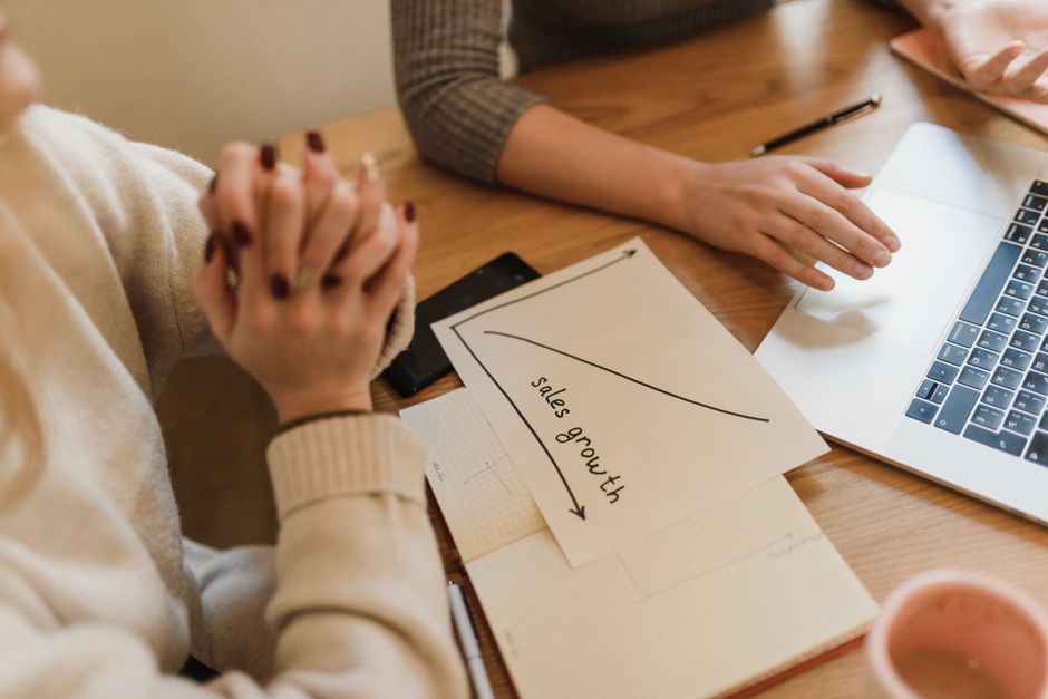 Duas pessoas em uma reunião de planejamento estratégico, analisando gráficos e discutindo crescimento de vendas.