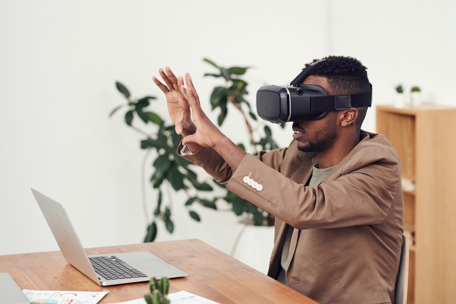 Homem usando óculos de realidade virtual em ambiente de escritório, explorando novas tecnologias.