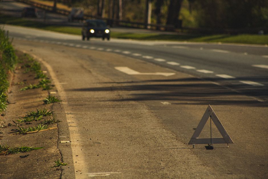 Sinal de trânsito de emergência na margem da estrada, indicando atenção e prevenção para motoristas.