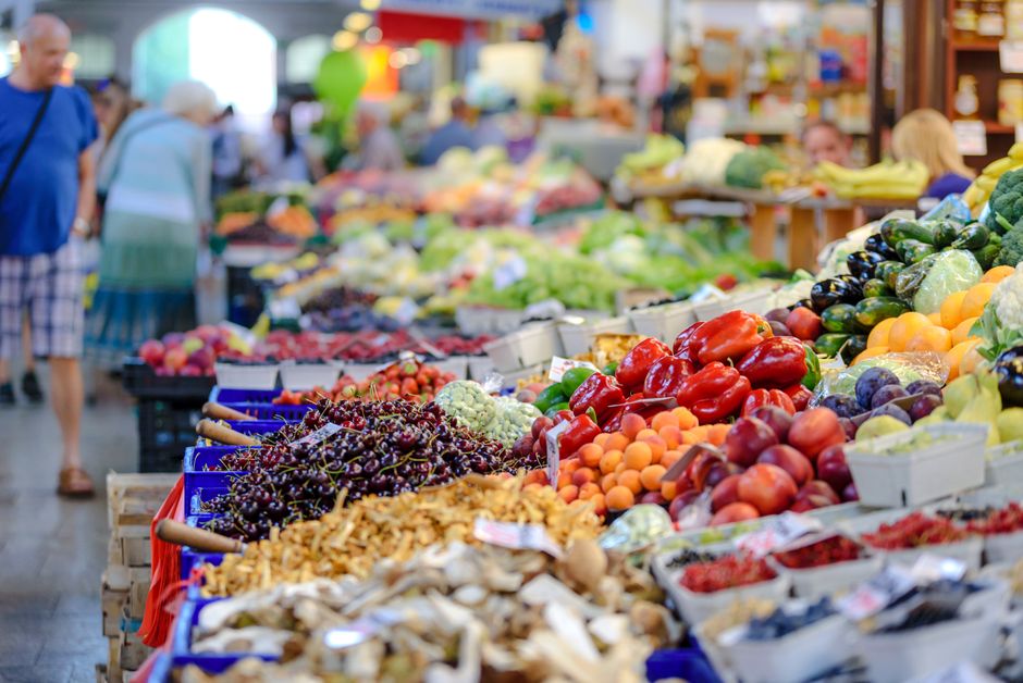 Uma variedade de frutas e vegetais frescos exibidos em uma feira, destacando a diversidade de alimentos naturais disponíveis em espaços ao ar livre.