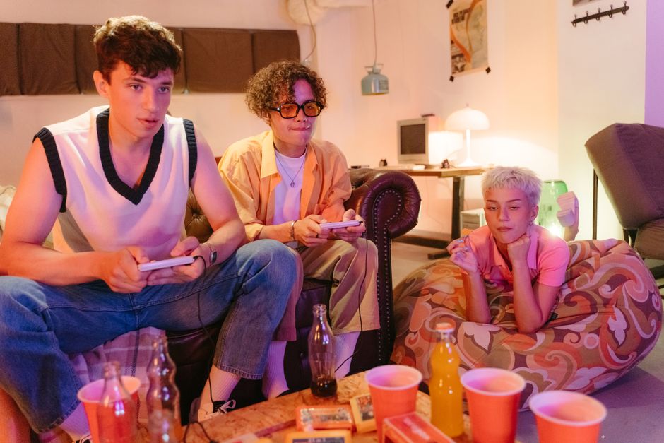 Jovens adultos jogando videogame em um ambiente de lazer com amigos, em uma sala confortável com iluminação suave.