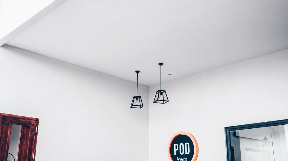 Imagem de um ambiente moderno com iluminação suspensa, decoração minimalista e placa de sinalização, ideal para ilustrar espaços de coworking ou escritórios criativos.