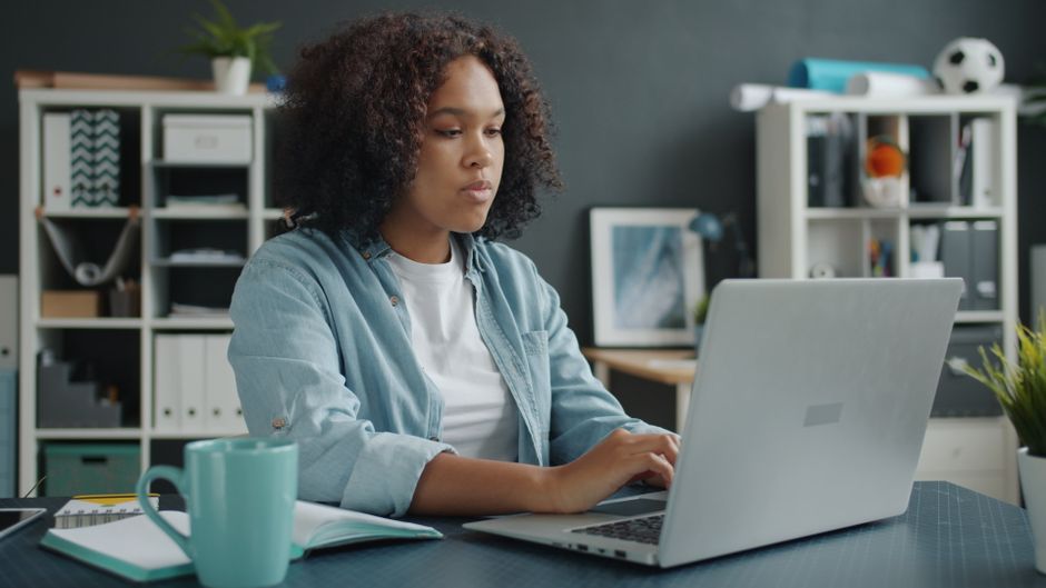 Mulher concentrada trabalhando em um ambiente de escritório com laptop, simbolizando produtividade e foco profissional.