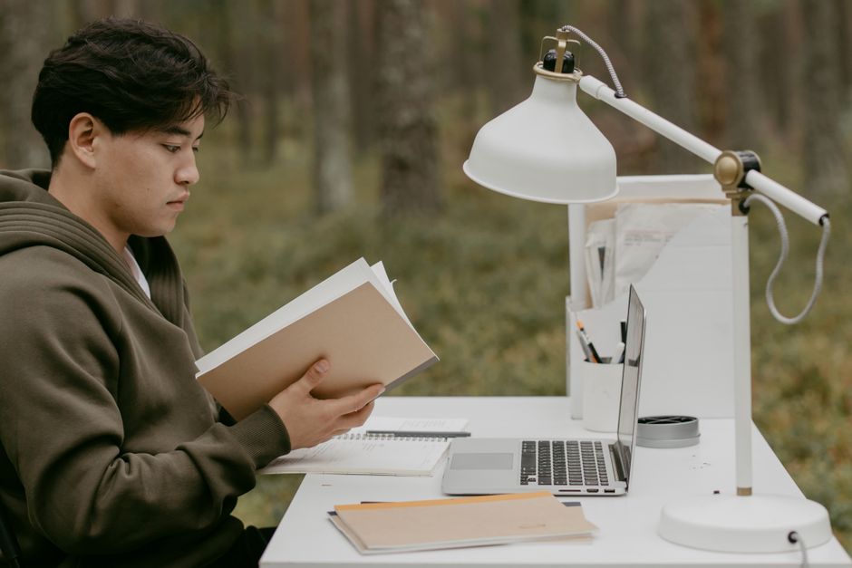 Jovem estudando e trabalhando ao ar livre, com foco em aprendizado e produtividade em um ambiente natural.