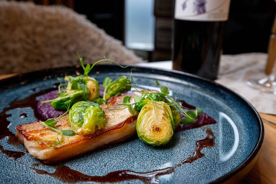 Prato sofisticado de peixe com vegetais e molho, apresentando uma composição culinária elegante para gastronomia e culinária refinada.