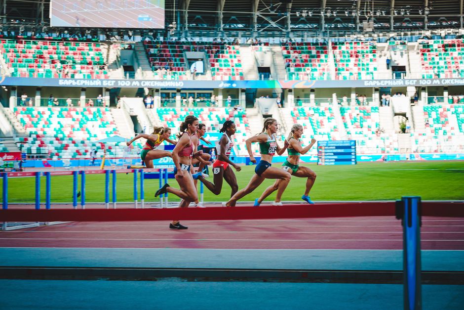 Atletas competindo em uma corrida de meia-distância em um estádio moderno, durante uma competição esportiva internacional.