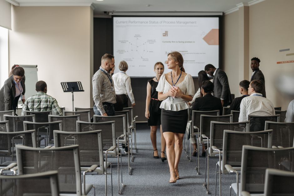 Imagem de uma conferência ou workshop corporativo com participantes discutindo relatos de progresso e estratégias de gestão.