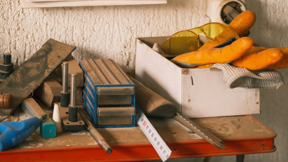 Imagem de uma bancada de trabalho de um artesão ou carpinteiro com ferramentas, alimentos e equipamentos variados.