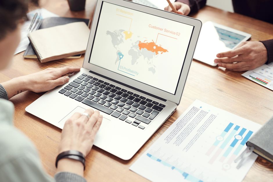 Reunião de equipe analisando estratégias de atuação global e atendimento ao cliente através de uma apresentação interativa em um ambiente de trabalho colaborativo.