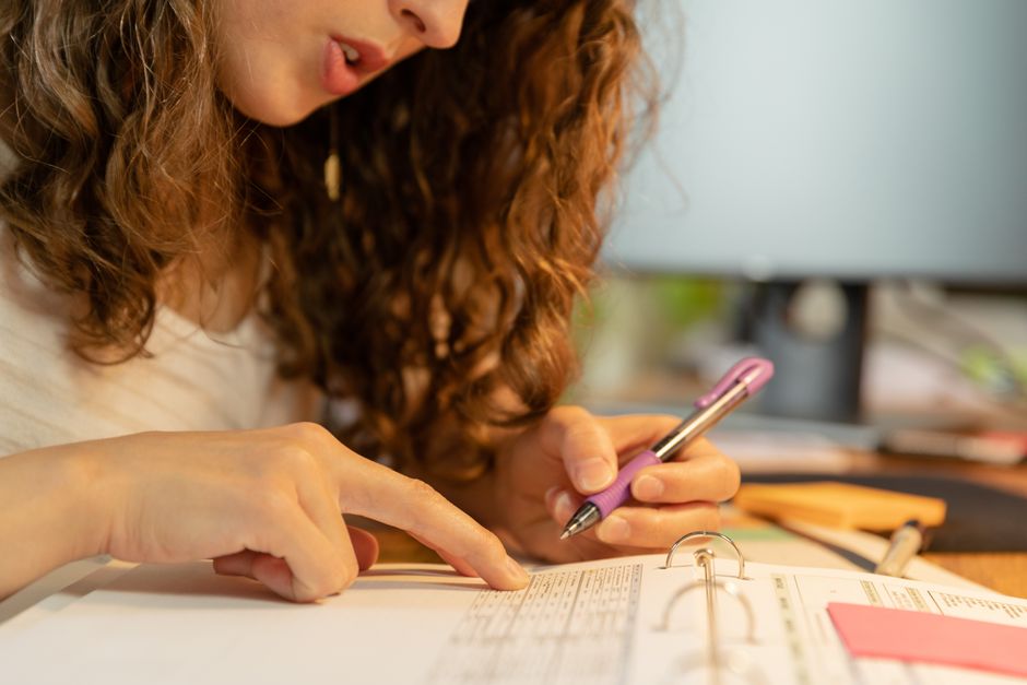 Mulher estudando ou revisando documentos com atenção, simbolizando dedicação aos estudos ou tarefas profissionais.