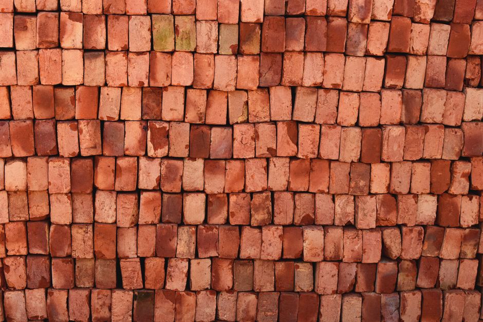 Imagem de uma parede feita com tijolos de argila, destacando a textura e o material de construção tradicional.