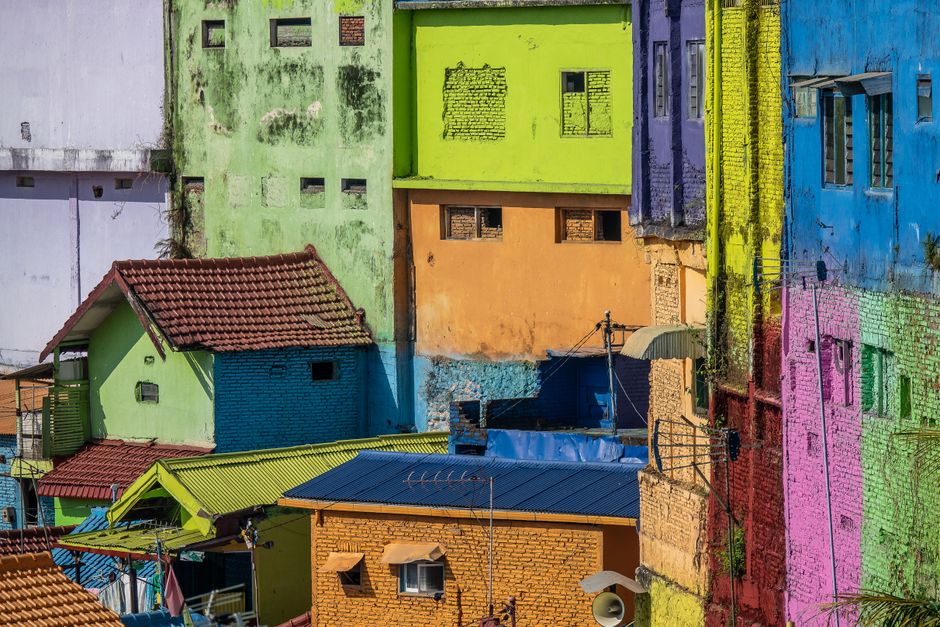 Conjunto de casas coloridas em uma área urbana com paredes pintadas em cores vibrantes, criando um cenário artístico e multicultural.