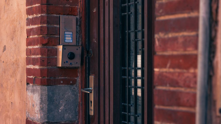 Imagem de uma porta de entrada de edifício residencial com controle de acesso eletrônico, destacando a segurança e tecnologia em residências.